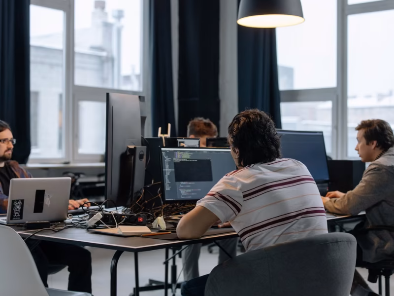 Team of developers collaborating around laptops in a modern tech office