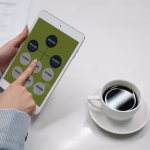 Hands holding a tablet with a diagram next to a cup of coffee on a desk