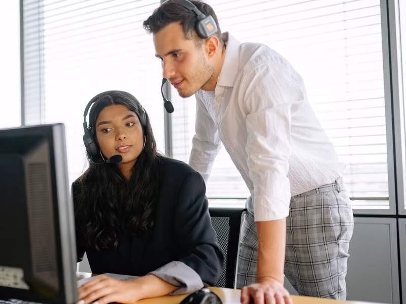 Two customer support agents working together in an office setting
